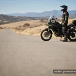 What Is Motorcycle Insurance? A Plain-English Guide for New Riders A rider in full gear standing beside a parked motorcycle on an open road in daylight